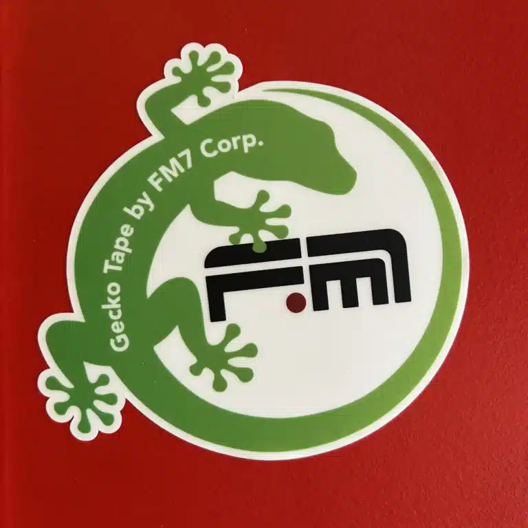FM7 Gecko-Sticker auf roter, glänzender Oberfläche – haftet ohne Kleber, wiederverwendbar und rückstandslos ablösbar.